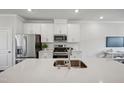 Bright kitchen with stainless steel appliances, white cabinets, and a large island featuring a modern faucet at 659 Mirkwood Ave, Apex, NC 27523