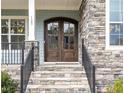 Inviting entrance with beautiful wooden double doors and stone steps leading to the charming front porch at 123 Stone Park Dr, Wake Forest, NC 27587