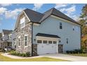 Side view of a home with a two-car garage, stone accents, and well-maintained landscaping at 123 Stone Park Dr, Wake Forest, NC 27587