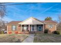 Inviting brick home with a welcoming front porch, classic design, and well-maintained lawn at 1303 Cherry Dr, Burlington, NC 27215
