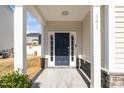 Covered front porch with a blue front door, stone accents, and well-maintained landscaping at 141 W Falcon Ct., Clayton, NC 27520