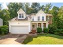 Two-story home with an attached garage and inviting front porch surrounded by mature trees at 2310 Woodbury Dr, Hillsborough, NC 27278