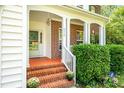 Inviting front porch with brick steps, columns, and lush greenery at 2310 Woodbury Dr, Hillsborough, NC 27278