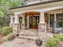 Inviting front porch with stone pillars, flagstone flooring, and double wood doors, creating a warm welcome at 2617 Jones Ferry Rd, Chapel Hill, NC 27516