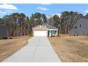 View of a single-story house with a stone facade and long driveway amid a natural landscape at 290 Forest Meadow Ln, Franklinton, NC 27525
