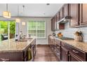 Well-lit kitchen with granite countertops, dark cabinets, and a window overlooking the backyard at 428 Morgan Ridge Rd, Holly Springs, NC 27540