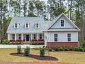 Charming two-story home featuring a well-manicured lawn, blue door, dormer windows, and a welcoming porch at 515 Sanctuary Trl, Cameron, NC 28326