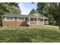 Beautiful brick home with a covered porch and carport in a lush green yard at 709 Fitzgerald Dr, Raleigh, NC 27610
