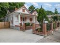 Inviting front exterior features brick accents, a black iron fence, and lush landscaping framing this charming home at 905 N Hyde Park Ave, Durham, NC 27701