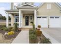 Inviting front entrance with well-maintained landscaping, a cozy porch, and a black front door at 104 Sage Oak Ln, Holly Springs, NC 27540