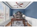 Stylish home office featuring classic blue walls, plantation shutters, a ceiling fan and built in bookshelves at 1233 Dunn Creek Xing, Wake Forest, NC 27587