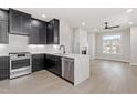 Open-concept kitchen with black cabinets, stainless steel appliances, island, and light wood floors adjoining living space at 226 Woodsborough Pl, Raleigh, NC 27601