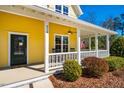 Inviting covered porch with white columns, ceiling fan, rocking chairs, and well-maintained shrubs at 314 Tobacco Farm Way, Chapel Hill, NC 27516