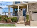 A cozy front porch featuring brick columns, a black metal railing, and neatly trimmed landscaping at 319 Brinkley Cir, Mebane, NC 27302