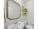 Stylish half-bathroom featuring a modern sink, decorative mirror, and floating shelves at 3408 Dropseed Dr, Apex, NC 27502