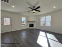 Bright living room with a fireplace, dark wood floors, a ceiling fan and windows providing ample natural light at 394 Springtooth Dr, Zebulon, NC 27597
