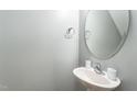 Clean half-bathroom with pedestal sink, decorative oval mirror, and chrome fixtures at 410 Pintail Ct, Durham, NC 27704