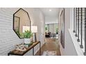 Inviting hallway with brick accent wall, decorative mirror, console table, and staircase at 422 Belgian Red Way, Wake Forest, NC 27587