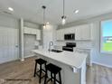 Well-lit kitchen with a central island, modern appliances, subway tile backsplash, and wood flooring at 472 Springtooth Dr, Zebulon, NC 27597