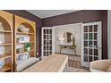Stylish home office with modern shelving and French doors leading to another room at 50 Granite Falls Way, Youngsville, NC 27596