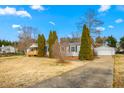 Exterior view of a charming single-story home with a detached garage and well-kept yard at 5636 Thom Rd, Mebane, NC 27302