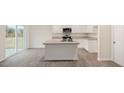 Well-lit kitchen with island, white cabinets, gray countertop, and stainless steel microwave at 6032 Sodium St, Raleigh, NC 27610