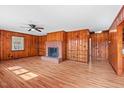 Spacious living room with wood paneled walls, a ceiling fan, and a brick fireplace at 7415 Old Oxford Rd, Bahama, NC 27503