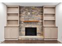 Inviting fireplace featuring stone surround, a wood mantle, and custom built in shelving at 7725 Longstreet Dr, Raleigh, NC 27615