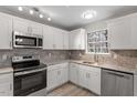 Bright kitchen featuring stainless steel appliances, white cabinets and stone backsplash at 8341 Wynewood Ct, Raleigh, NC 27616