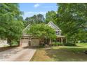 Charming two-story home with a manicured lawn, mature trees, and a welcoming front porch at 94 Fawn Hill Ct, Garner, NC 27529