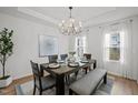 Dining room with modern chandelier, wood table with upholstered chairs and bench on a carpet runner, and natural light at 1026 Janiskee Rd, Durham, NC 27703