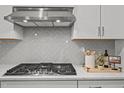 Modern kitchen featuring stainless steel hood, gray backsplash, and light countertops at 1026 Janiskee Rd, Durham, NC 27703