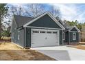 Attached two-car garage featuring carriage doors, stylish lights, and a concrete driveway at 109 Averly Ct, Stem, NC 27581