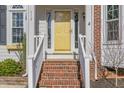 Inviting front entrance with brick steps leading to a bright yellow door, number 112 on the side at 112 Solstice Cir, Cary, NC 27513