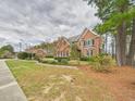 A spacious brick home with mature trees, a well-manicured lawn, and classic black shutters on a cloudy day at 1201 Clematis St, Knightdale, NC 27545