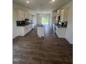 Bright kitchen with white cabinetry, dark backsplash, stainless steel appliances, and hardwood floors at 432 Springtooth Dr, Zebulon, NC 27597