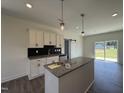 Open kitchen boasts a granite island, recessed lighting, and views of the backyard through sliding glass doors at 432 Springtooth Dr, Zebulon, NC 27597