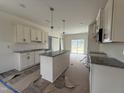 Spacious kitchen featuring white cabinets, granite countertops, an island, and sliding glass doors to backyard at 432 Springtooth Dr, Zebulon, NC 27597