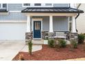Inviting front porch with stone accents, elegant columns, a cozy bench, and a blue front door at 105 Palladium Ct, Elon, NC 27244