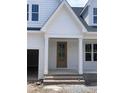 A close-up of the front entrance featuring a charming, light wood front door, brick base and white posts at 108 Pointe Park Cir, Holly Springs, NC 27540