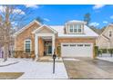 Inviting home showcasing a stone facade, well-kept lawn, and a convenient two-car garage during the snowy season at 208 Abigail Ln, Gibsonville, NC 27249