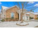Cozy home featuring a stone exterior, picturesque landscaping, and a two-car garage, all blanketed in a dusting of snow at 208 Abigail Ln, Gibsonville, NC 27249