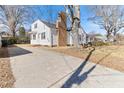 View of a charming white home with a brick chimney and a long, paved driveway on a sunny day at 307 Gordon St, Roxboro, NC 27573