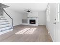 Bright living room featuring light-colored hardwood floors, a white fireplace, and staircase with blue trim at 307 Gordon St, Roxboro, NC 27573