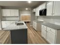 Modern kitchen with white cabinets, gray countertops, stainless steel sink and plank flooring at 343 Magnolia Run Way, Benson, NC 27504