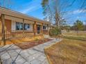 Inviting covered front porch with brick and stone walkway, complemented by professionally landscaped flower beds and exterior shutters at 427 Watson Rd, Efland, NC 27243