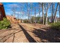 Large, tree-lined backyard showcasing a spacious area and a wooden deck at 6312 New Market Way, Raleigh, NC 27615
