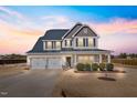 Inviting two-story home features a two-car garage, covered porch, and manicured landscaping at sunset at 6804 Arlington Oaks Trl, Raleigh, NC 27603