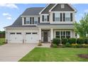Two-story home with a three-car garage, a cozy covered porch, and manicured landscaping at 6804 Arlington Oaks Trl, Raleigh, NC 27603
