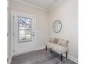 Bright foyer features a stylish bench, round mirror, and a glass-paned door with wood-look flooring at 723 Toulouse Ct, Cary, NC 27519